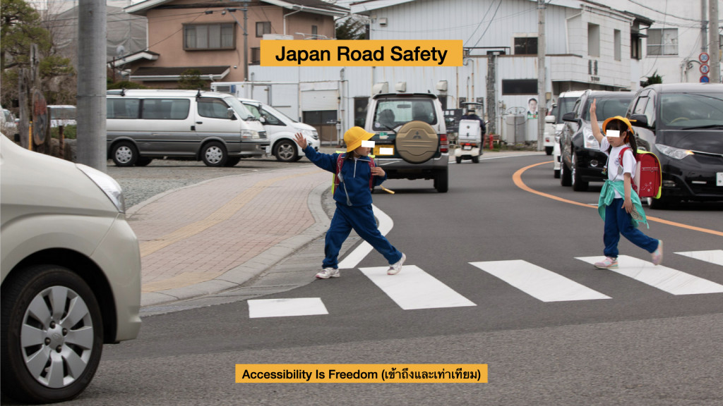 ภาพ ภาพ นักเรียนตัวน้อยๆ กำลังข้ามถนน ยกมือเป็นสัญญาณให้รถเห็นได้ง่าย